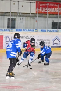 Zweikampf um den Puck zwischen Spielern in blauen und rot-weißen Trikots