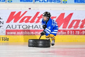 Junger Spieler schiebt beim Krafttraining einen Reifen über das Eis