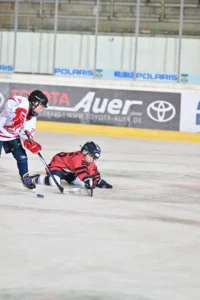 Spieler rutscht nach einem Zweikampf bäuchlings über das Eis