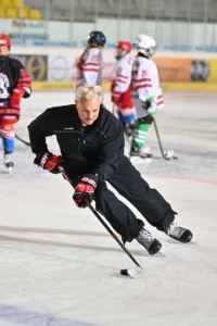 Trainer zeigt mit dem Puck am Schläger eine Laufübung vor
