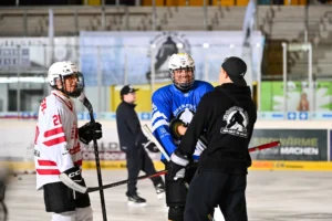 Trainer im Gespräch mit Spielern in blauen und rot-weißen Trikots