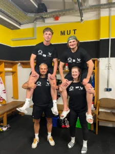 Das Trainerteam posiert in der Kabine unter dem Schriftzug Mut