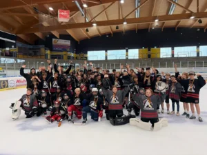 Jubelndes Gruppenfoto der Campteilnehmer mit Medaillen in der Eishalle